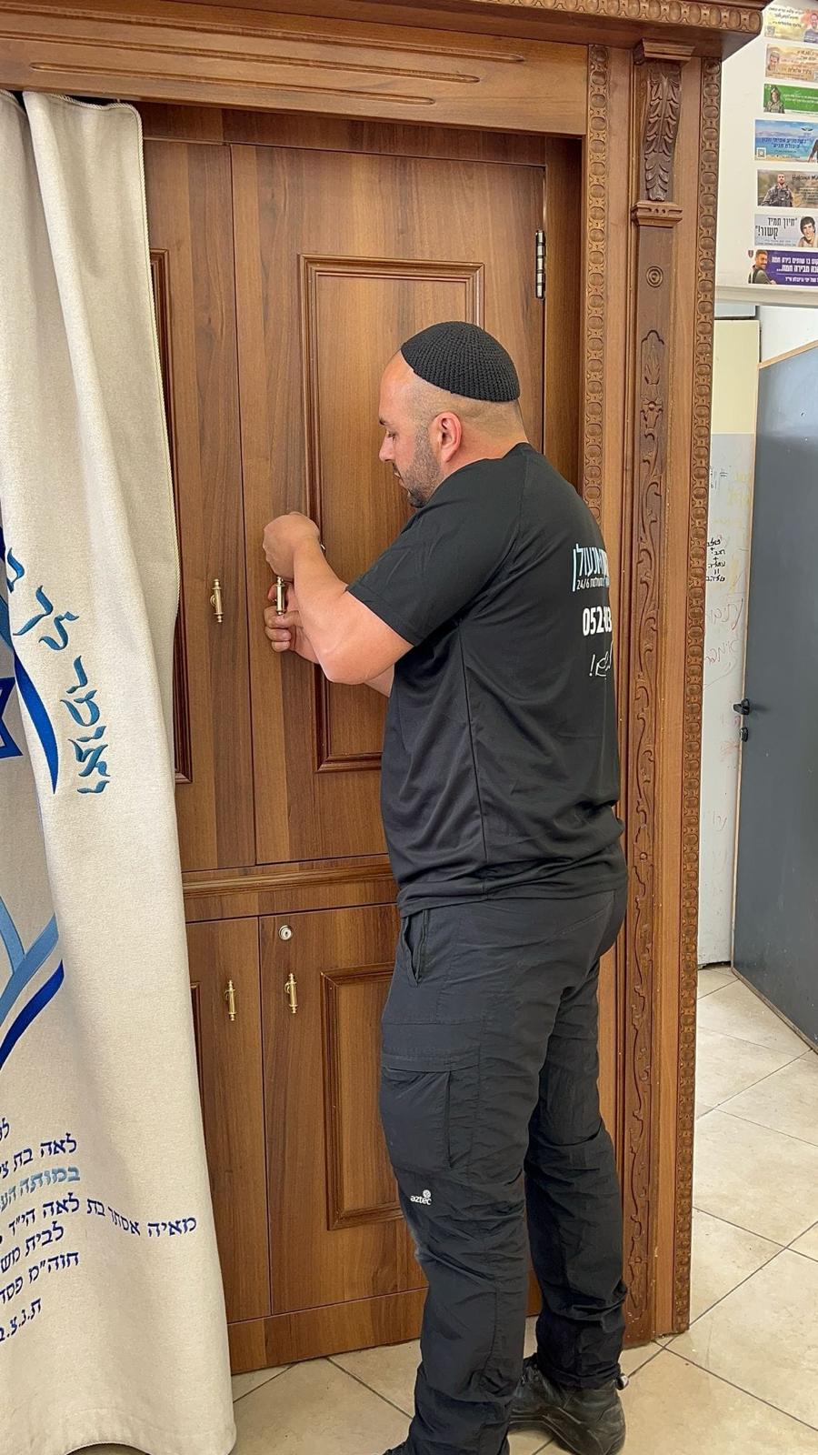 שמעון המנעולן מתקן את מנעול דלת העץ המגולפת של ארון קודש בבית כנסת